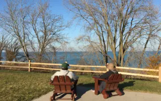 two people sit on adirondack chairs overlooking Lake Michigan while on a retreat